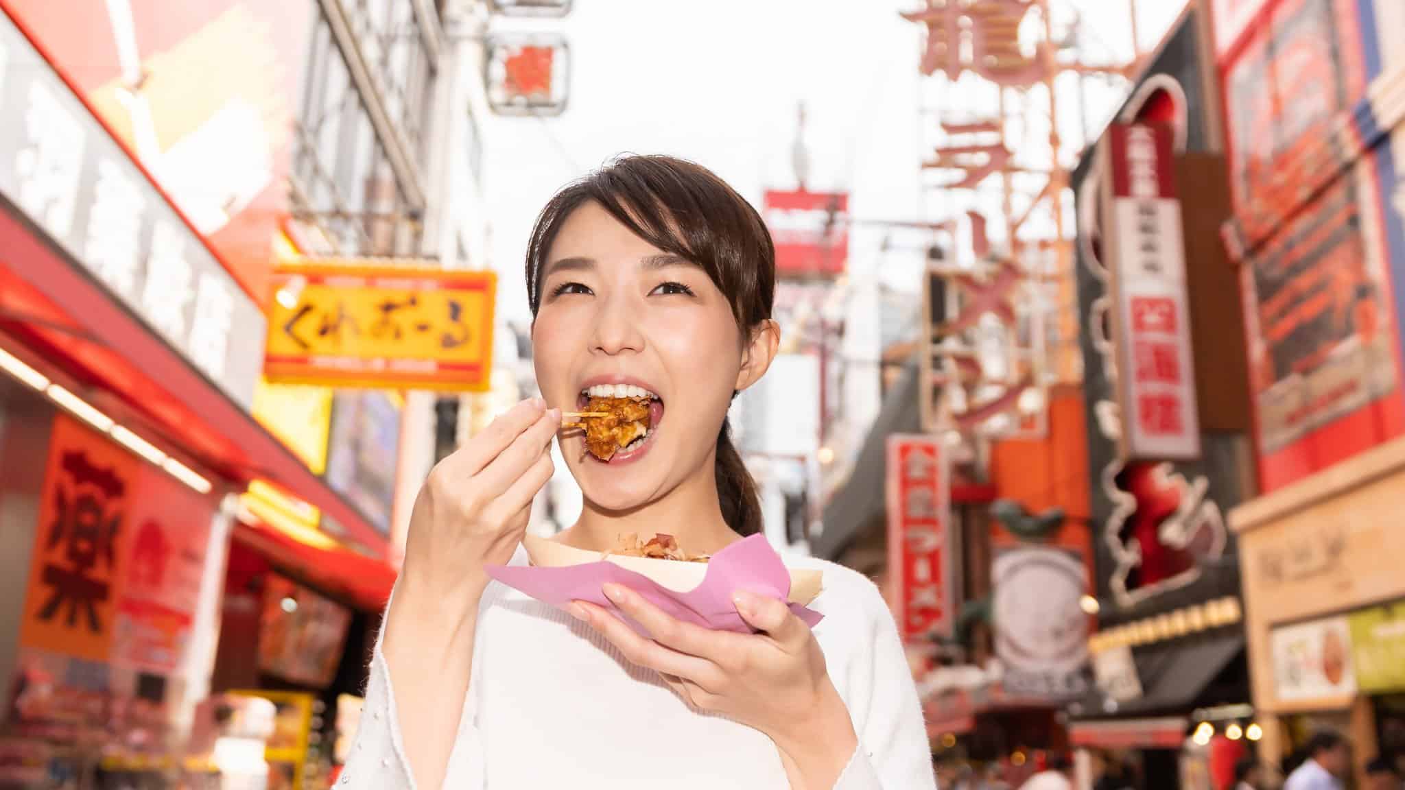 महिला टूथपिक से ताकोयाकी खा रही है